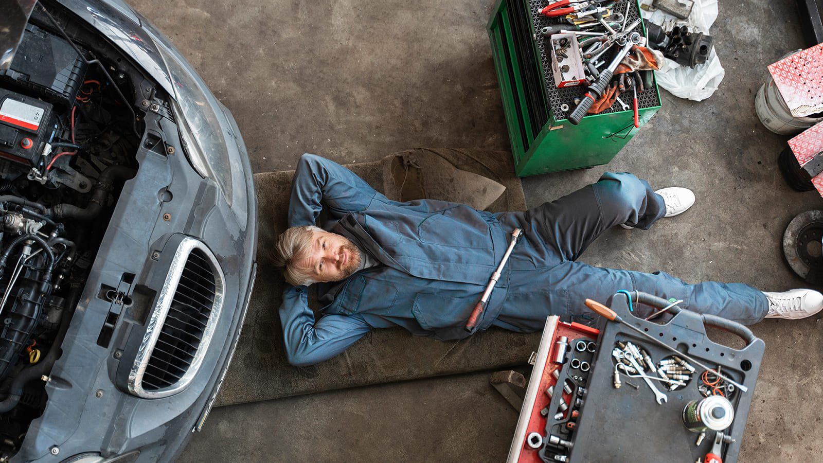Technicien automobile allongé sous un véhicule pour diagnostic et réparation mécanique — Garage de Saint-Barthélemy, spécialiste Ford et multi-marques CarXpert près d'Échallens, Vaud